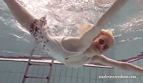 Ein schlankes blondes Mädchen schwimmt unter Wasser